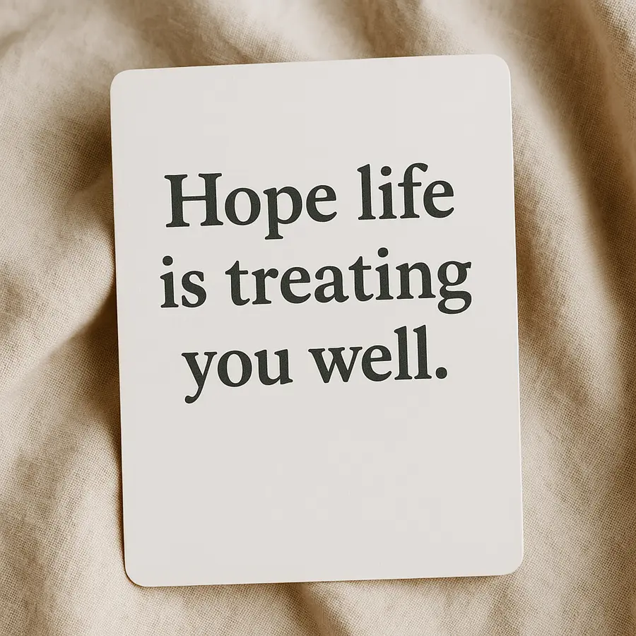 Close-up of a card reading "Hope life is treating you well" on a soft beige fabric background.